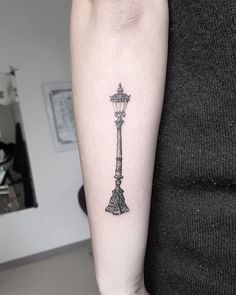 a black and white photo of a lamp post tattoo on the arm