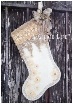 a christmas stocking hanging on a wooden fence with beads and flowers in the corner