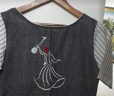 an embroidered dress hanging on a wooden hanger next to a striped t - shirt