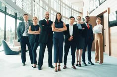 a group of business people standing in front of a large glass window with their arms crossed