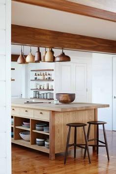 an island in the middle of a kitchen with two stools and plates on it