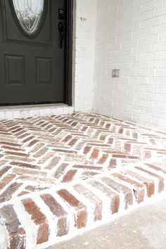 a black door is on the side of a white brick building