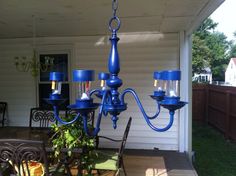 a blue chandelier hanging from the side of a house next to a table and chairs