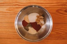 a metal bowl filled with spices on top of a wooden table