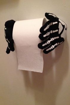 a roll of toilet paper that has been wrapped in black and white skeleton gloves on it