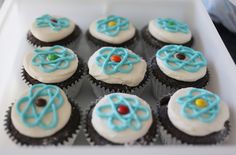 cupcakes with white frosting and blue icing are arranged in a box