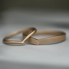 two gold wedding rings sitting side by side on top of a white surface with one ring in the middle