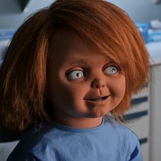 a doll with red hair and big eyes looks at the camera while standing in front of a sink