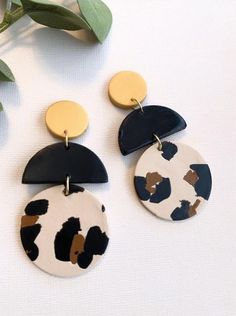 two pairs of black, white and gold dangle earrings on top of a table