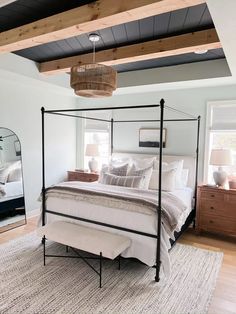 a bedroom with a four poster bed and white linens on the pillows, along with a large mirror