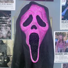 a pink and black jacket hanging on a wall next to pictures with people in the background