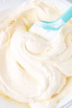 whipped cream in a bowl with a blue spatula on the top and white icing