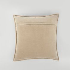 a beige pillow on a white wall with a light brown border around the edges and an off - white background