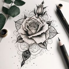 a black and white drawing of a rose on paper next to some markers, pens and pencils