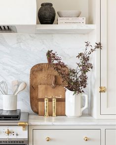 a cutting board and utensils on a counter in a kitchen with white cabinets