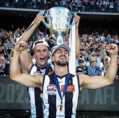 two men holding up a trophy in front of a crowd