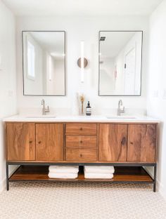 a bathroom with two mirrors above the sinks and wooden cabinets on both sides of the sink