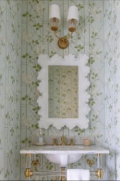 a white sink sitting under a bathroom mirror next to a wall mounted faucet