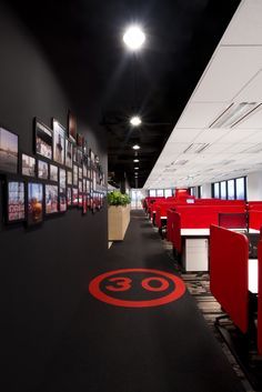 an empty office with red desks and pictures on the wall behind them in black and white