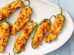 four stuffed peppers on a white plate with blue wood table in the backgroud