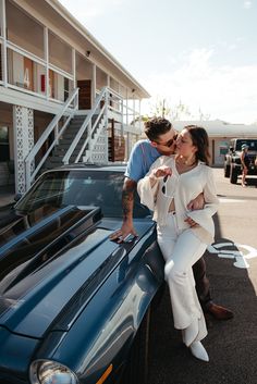 a man and woman kissing next to a car