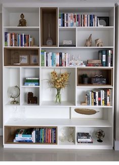 a bookshelf filled with lots of books and vases on top of it