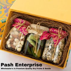 four jars filled with different types of nuts in a yellow gift box on a table