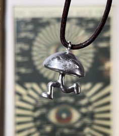 This handmade Metal Casted Earthbound Enemy "Ramblin' Evil Mushroom" Necklace is a unique accessory inspired by the popular video game. Unique Design: The necklace features a metal casted design of the iconic "Ramblin' Evil Mushroom" enemy from Earthbound, making it a must-have for fans of the game. Unisex Appeal: This necklace is suitable for both men and women, making it a versatile accessory to complement any outfit. Add a touch of nostalgia and style to your look with this eye-catching Earthbound-inspired necklace! Dimensions: Height - 18mm Width - 18mm Adjustable Themed Necklace For Collectors, Unique Adjustable Mushroom-shaped Jewelry, Handmade Adjustable Themed Necklace, Handmade Adjustable Novelty Necklace, Handmade Novelty Adjustable Necklace, Adjustable Spiritual Necklace With Mushroom Design, Evil Mushroom, 3d Printed Necklace, Mushroom Resin