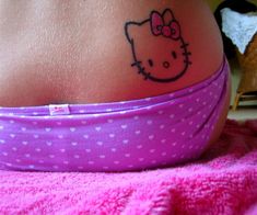 a hello kitty tattoo on the side of a woman's stomach, with polka dots