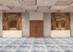 an empty ballroom with chandelier and wooden doors in the center, surrounded by carpeted flooring