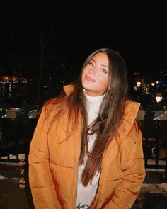 a woman standing in the snow at night with her hands on her hips and looking up