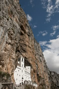 a large white building sitting on the side of a rocky cliff under a blue sky