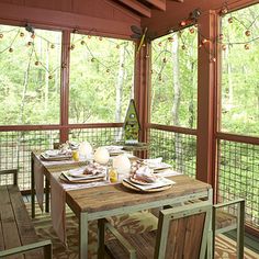 a table and chairs are set on the screened porch with wood flooring that overlooks trees