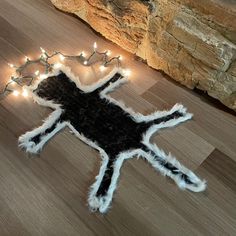 a black and white cat rug with lights on the floor next to a stone wall