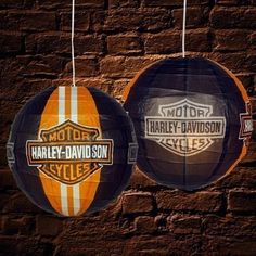 two harley davidson balls hanging from strings against a brick wall