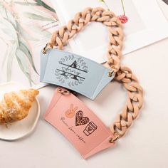 two pieces of jewelry sitting on top of a table next to a cup and plate