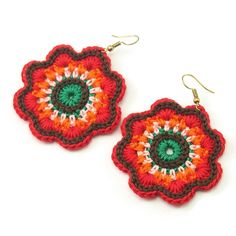 two crocheted flower shaped earrings with green and red beads on them, sitting next to each other