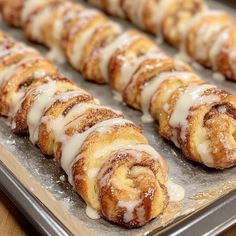 cinnamon rolls on a baking sheet with icing drizzled around them, ready to be baked