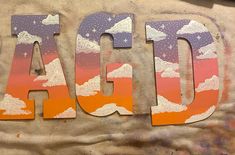 the letters are made up of paper and painted with pastel colors, clouds, and stars