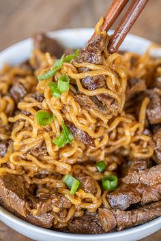 beef and noodles in a bowl with chopsticks sticking out of the meat to eat