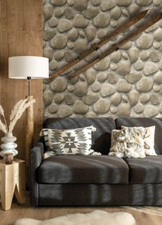 a living room with a couch, lamp and stone wallpaper on the back wall