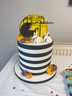 A tall cake that stands on a white board. The cake has black and white horizontal stripes. There is a cake topper that says ‘hey there pumpkin’, a yellow moon, a black and purple pram and two ghost dogs (Zero). There are a few purple and orange pumpkins dotted around the cake too. Nightmare Before Christmas Gender Reveal Cake, Chocolate Baby Shower Cake, Halloween Gender Reveal Cake, Nightmare Before Christmas Gender Reveal, Nightmare Before Christmas Baby Shower Ideas, Christmas Baby Shower Cake, Halloween Baby Shower Cake, 2023 Cakes