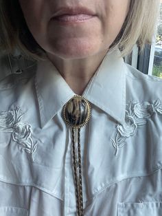 Step into the bold style of the 1980s with this Vintage Unisex Bolo Tie, a distinctive piece of vintage costume jewelry that captures the spirit of Western fashion. This versatile accessory features a classic bolo tie design, with intricately detailed tips and a stylish centerpiece that adds a touch of rugged elegance to any outfit. Bolo ties surged in popularity during the 1980s, becoming a fashion statement that transcended traditional Western wear and found its way into mainstream culture. Ce Vintage Lariat Bolo Ties For Rodeo, Vintage Adjustable Bolo Tie For Formal Occasions, Vintage Formal Bolo Tie Lariat, Vintage Gold Lariat Bolo Tie, Adjustable Vintage Lariat Necklace, Bolo Tie Women Outfit, Tie Women Outfit, Bolo Tie Women, Western Bolo Tie