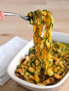 someone is eating zucchini noodles in a white bowl