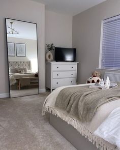 a bedroom with a large mirror on the wall and a teddy bear sitting on the bed