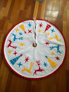 a white and red christmas tree skirt sitting on top of a wooden floor next to a clock