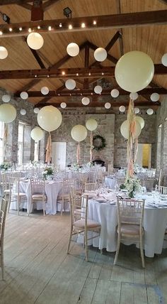 a room filled with lots of tables covered in white clothed tablecloths and balloons