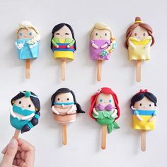 a hand holding a popsicle decorated with different types of children's avatars