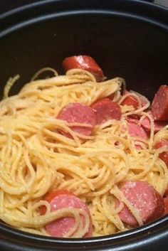 pasta with sausage and tomato sauce in a black pan on the stove top, ready to be cooked