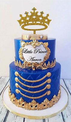 a blue and gold cake with a crown topper on it's tiers